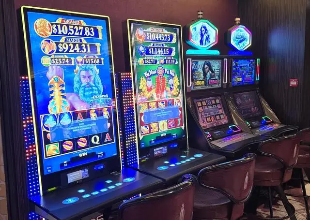 Two tall portrait-screen slot machines, Olympus Strikes with a Zeus figure and Fu Nan Fu Nu with Chinese artwork, standing beside two shorter cabinets topped with illuminated Voodoo Vixens and winter-themed signs.