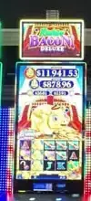 Bacon Deluxe title above Celebrity Reflection slot cabinets
