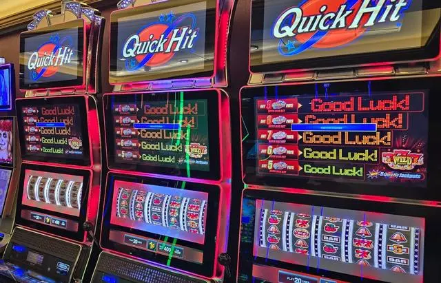 A curved bank of Quick Hit slot machines, each with a lit Quick Hit topper above a screen reading 'Good Luck!' beside the Quick Hit jackpot ladder, with more cabinets receding down the row.
