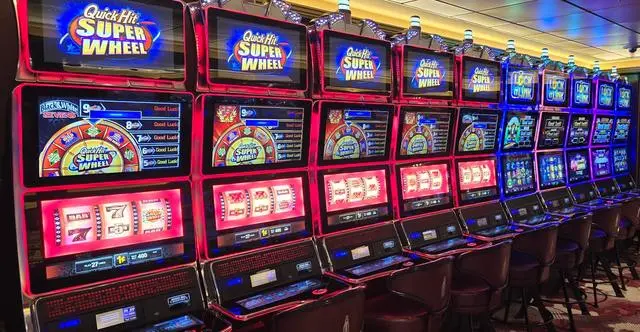 A long row of Quick Hit Super Wheel cabinets lit in red, giving way to a bank of Lock It Link machines lit in blue further down the row.