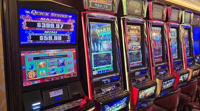 A Konami Quick Strike machine in the foreground showing Major and Mini jackpots with their posted ranges, followed by a receding row of Ainsworth cabinets including King Cat, Dragon Lines and Rumble Rumble.